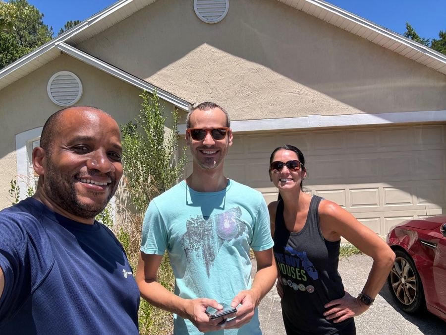 Chris with two team members in front of a house
