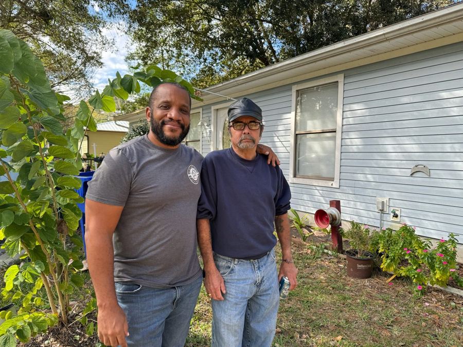 Chris with a homeowner outside a blue house